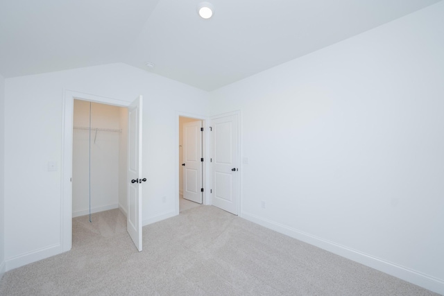 unfurnished bedroom with baseboards, a closet, lofted ceiling, and light colored carpet