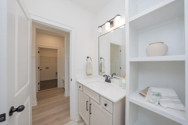 bathroom featuring a spacious closet, wood finished floors, and vanity