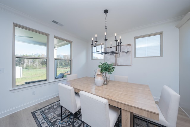 dining room featuring a notable chandelier, wood finished floors, visible vents, baseboards, and crown molding