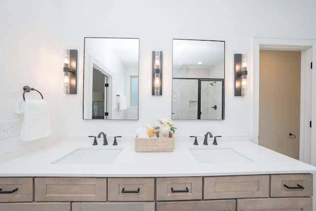 bathroom with double vanity, a marble finish shower, and a sink