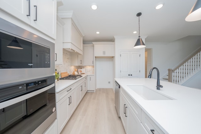 kitchen featuring hanging light fixtures, a sink, stainless steel appliances, light countertops, and backsplash