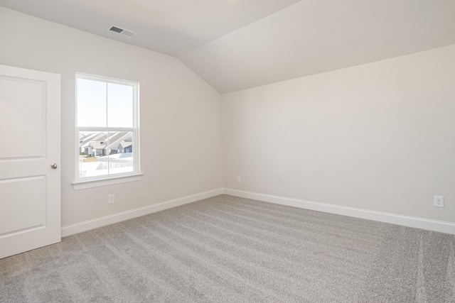 carpeted spare room featuring lofted ceiling, baseboards, and visible vents