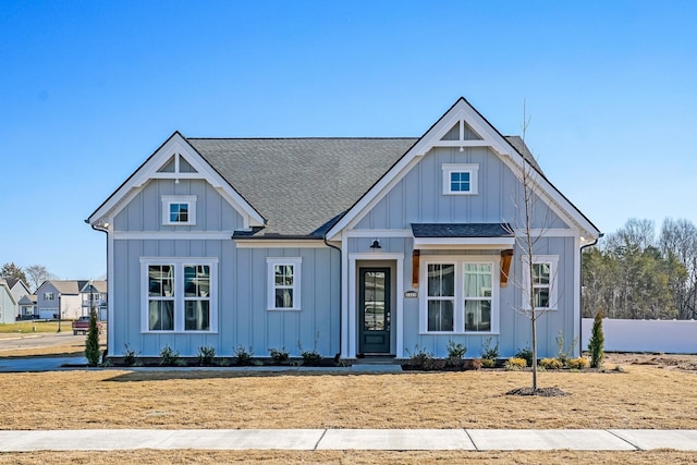 modern farmhouse with a shingled roof, board and batten siding, and fence