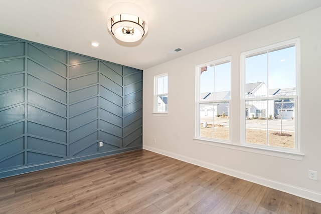 unfurnished room featuring light wood-type flooring, visible vents, and baseboards