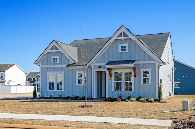 modern farmhouse style home featuring a shingled roof, board and batten siding, and fence