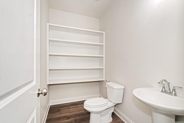 half bath featuring wood finished floors, a sink, toilet, and baseboards