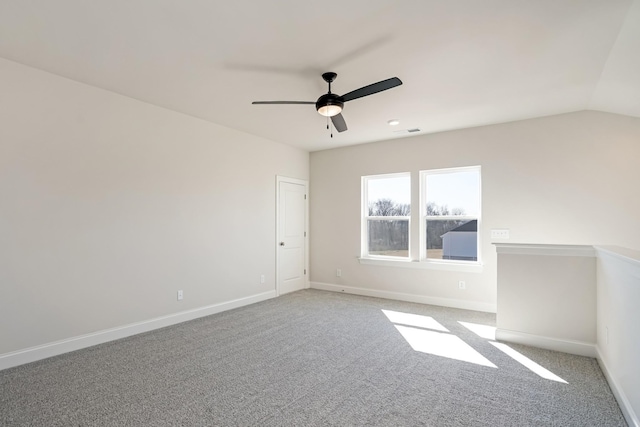 empty room featuring lofted ceiling, carpet, visible vents, and baseboards