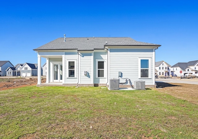 rear view of property featuring a lawn, cooling unit, and a residential view