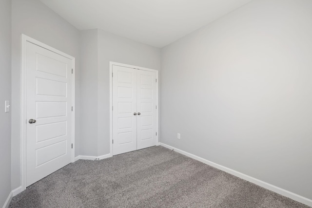 unfurnished bedroom with carpet, a closet, and baseboards