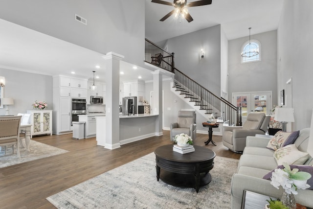 living room with baseboards, visible vents, a ceiling fan, dark wood-style floors, and stairway