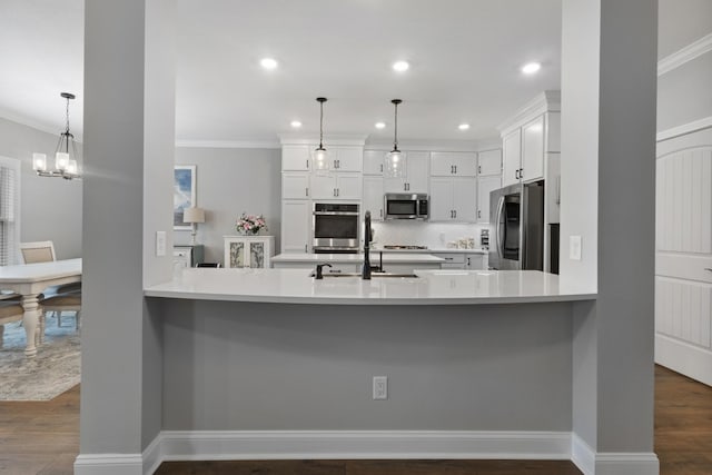 kitchen with white cabinets, dark wood-style floors, appliances with stainless steel finishes, a peninsula, and light countertops