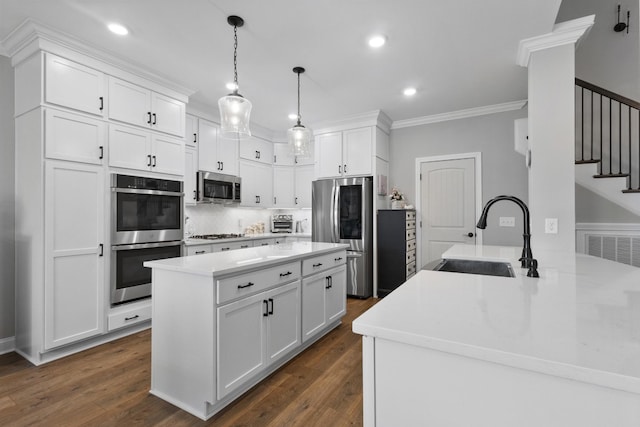 kitchen with stainless steel appliances, dark wood-style flooring, a sink, white cabinets, and crown molding