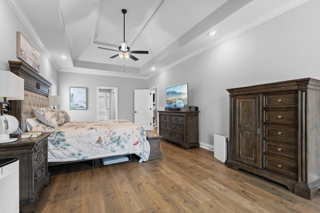 bedroom featuring baseboards, a tray ceiling, wood finished floors, and crown molding