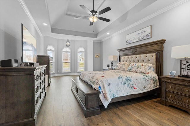 bedroom featuring hardwood / wood-style flooring, ceiling fan, a tray ceiling, and ornamental molding