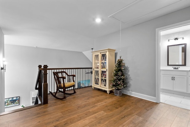 sitting room with attic access, light wood-style flooring, and baseboards