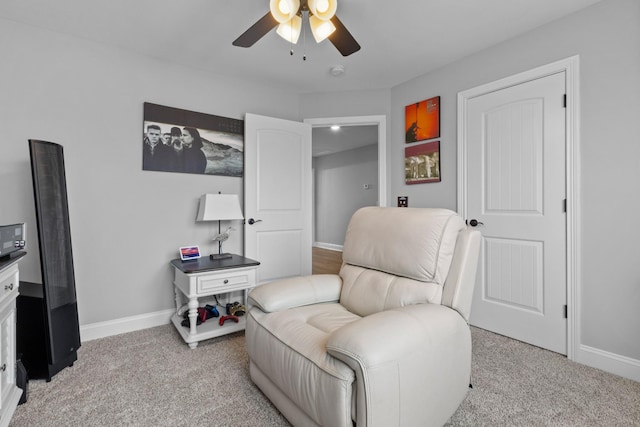 living area with carpet floors, a ceiling fan, and baseboards