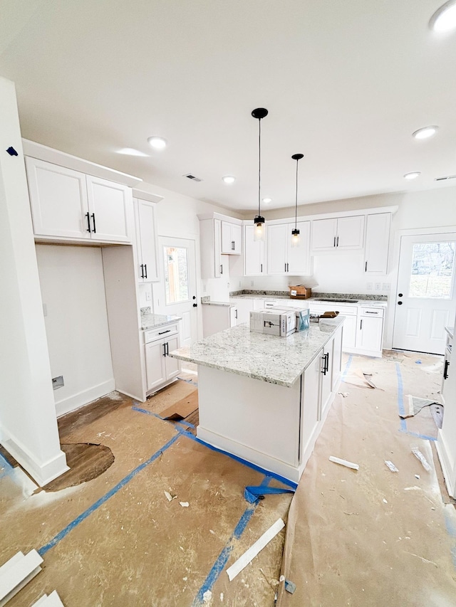 kitchen featuring light stone counters, pendant lighting, white cabinetry, and a kitchen island