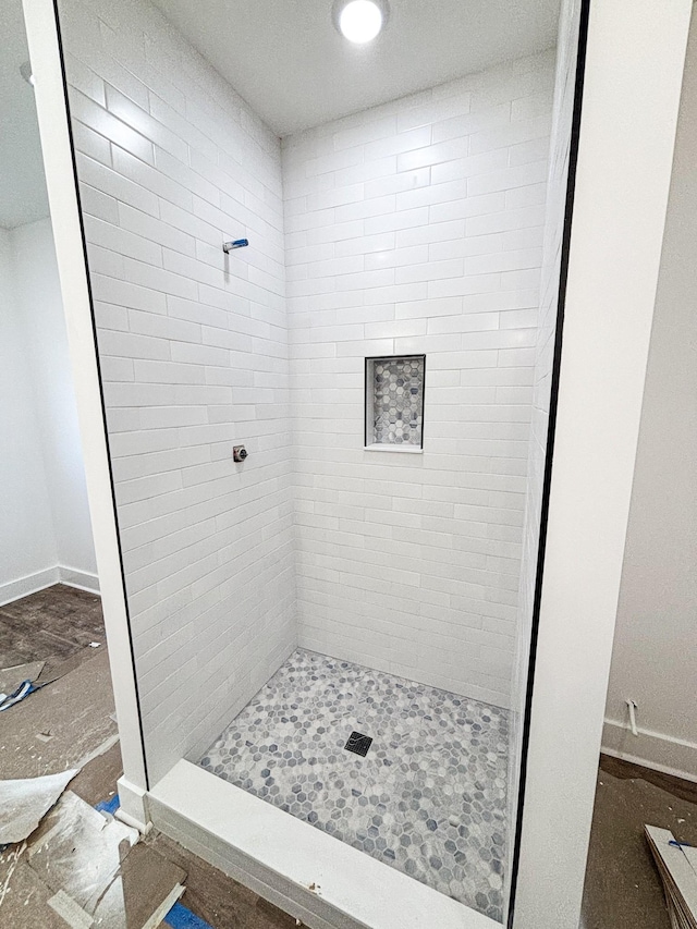 bathroom featuring a tile shower and baseboards