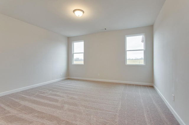 spare room with light colored carpet, visible vents, and baseboards