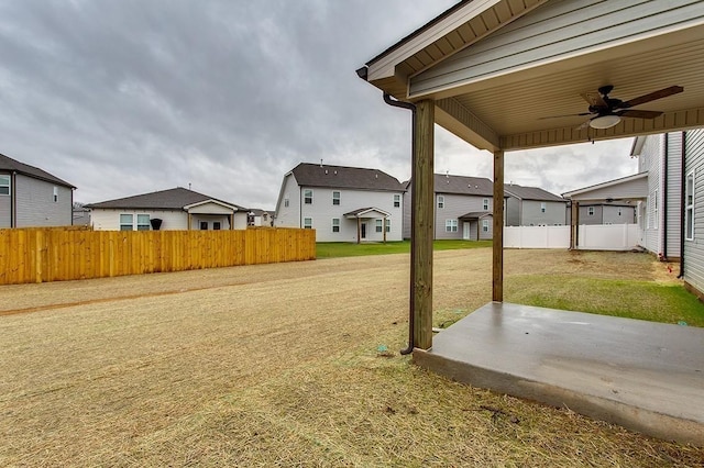 view of yard with a patio, a residential view, fence, and a ceiling fan