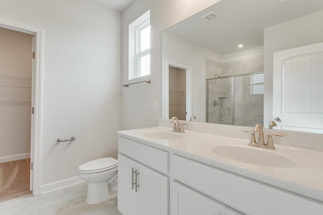 bathroom with a stall shower, a sink, toilet, and a walk in closet