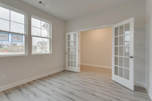 spare room with baseboards, visible vents, wood finished floors, and french doors