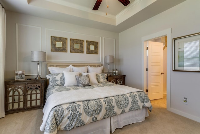 carpeted bedroom with a raised ceiling, crown molding, baseboards, and ceiling fan