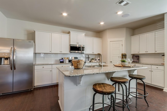 kitchen with appliances with stainless steel finishes, visible vents, a sink, and white cabinetry