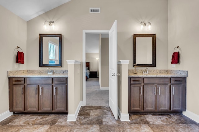 ensuite bathroom with lofted ceiling, ensuite bath, two vanities, and visible vents