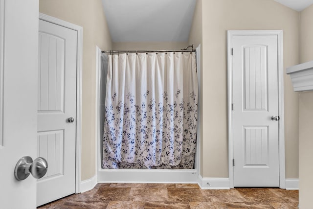 full bath with curtained shower, lofted ceiling, and baseboards