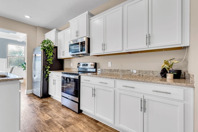 kitchen featuring light wood finished floors, white cabinets, appliances with stainless steel finishes, light stone counters, and recessed lighting