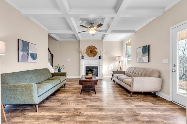 living area featuring coffered ceiling, wood finished floors, baseboards, beam ceiling, and a glass covered fireplace