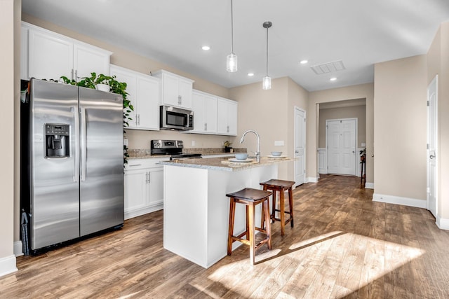 kitchen with wood finished floors, appliances with stainless steel finishes, a sink, and visible vents