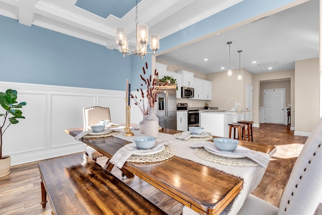 dining space featuring a notable chandelier, a decorative wall, visible vents, light wood-style floors, and beamed ceiling