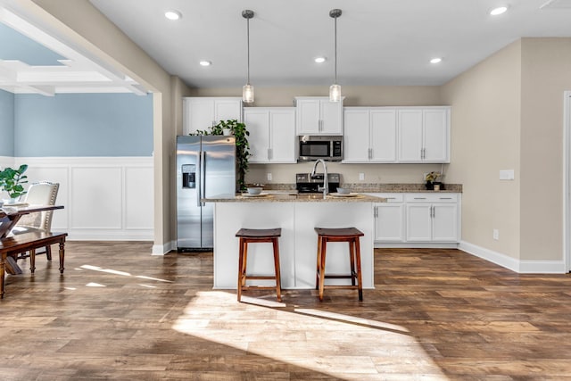 kitchen featuring stainless steel appliances, white cabinetry, dark wood finished floors, and an island with sink