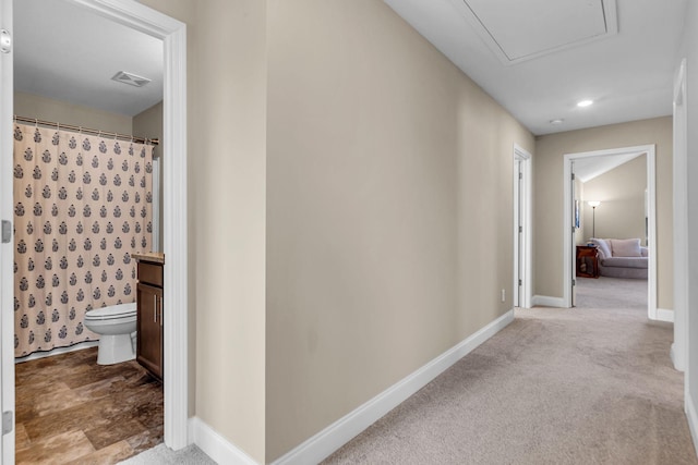 hall featuring carpet flooring, visible vents, and baseboards