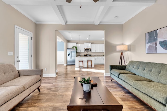 living area with light wood-style floors, ceiling fan, baseboards, and beamed ceiling