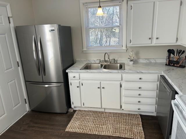 kitchen featuring light stone counters, dark wood-type flooring, a sink, white cabinetry, and appliances with stainless steel finishes