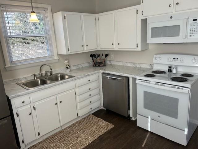 kitchen with white appliances, a sink, dark wood finished floors, and white cabinetry