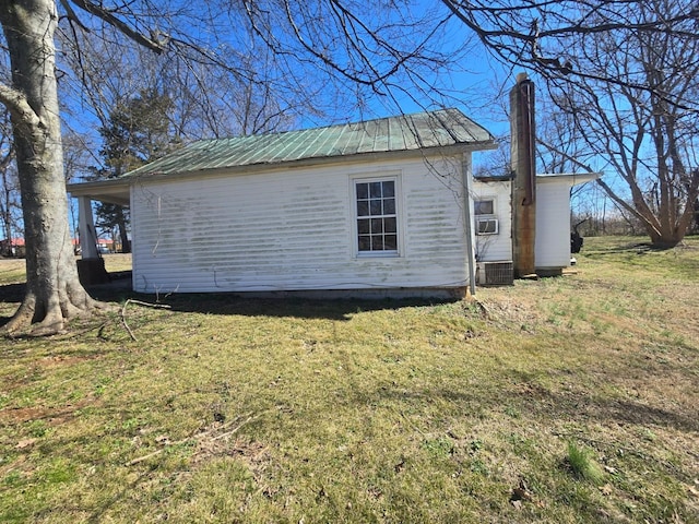 view of home's exterior with cooling unit, metal roof, and a lawn