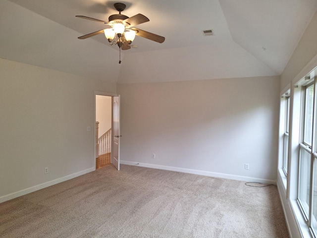 unfurnished room with light carpet, vaulted ceiling, and baseboards