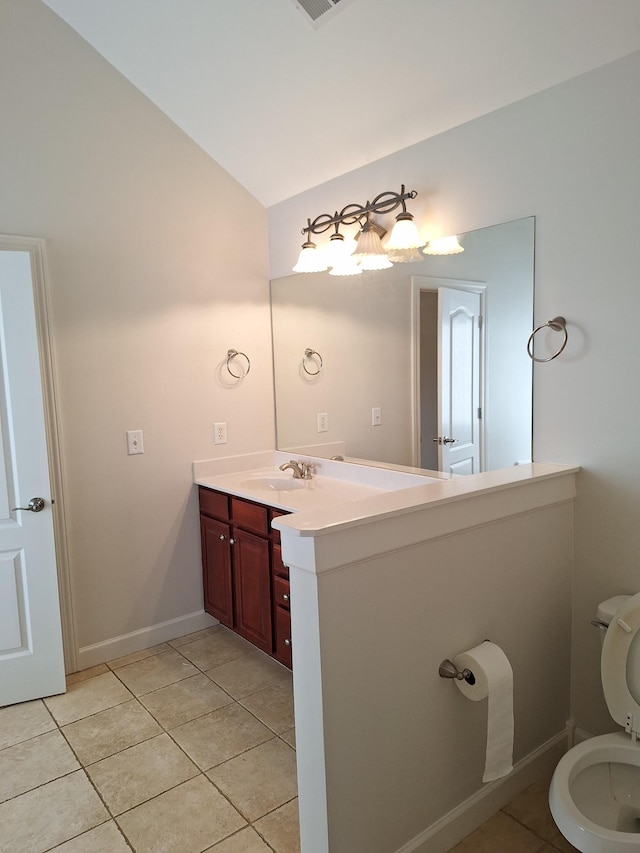 bathroom featuring lofted ceiling, toilet, vanity, baseboards, and tile patterned floors