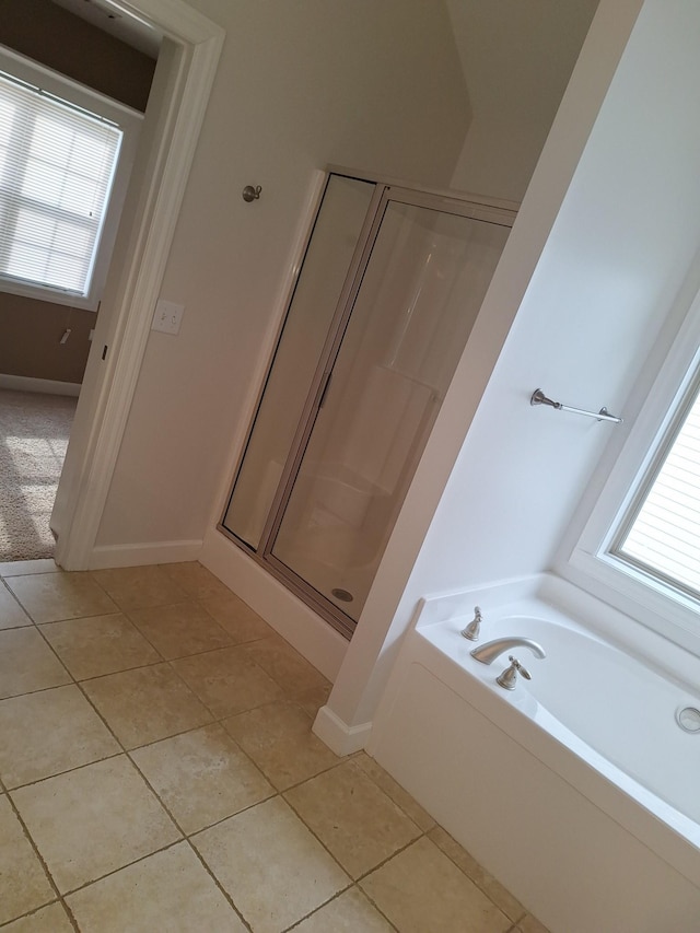 full bath featuring a garden tub, tile patterned flooring, baseboards, and a shower stall