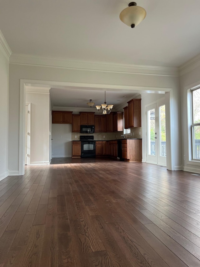 unfurnished living room featuring dark wood-type flooring, ornamental molding, and baseboards