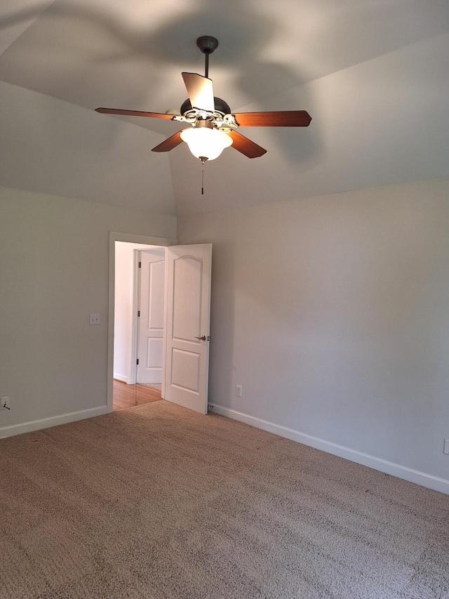 empty room with light carpet, ceiling fan, lofted ceiling, and baseboards