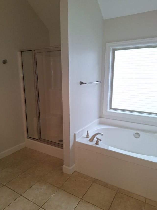 full bath featuring a garden tub, a stall shower, vaulted ceiling, tile patterned flooring, and baseboards