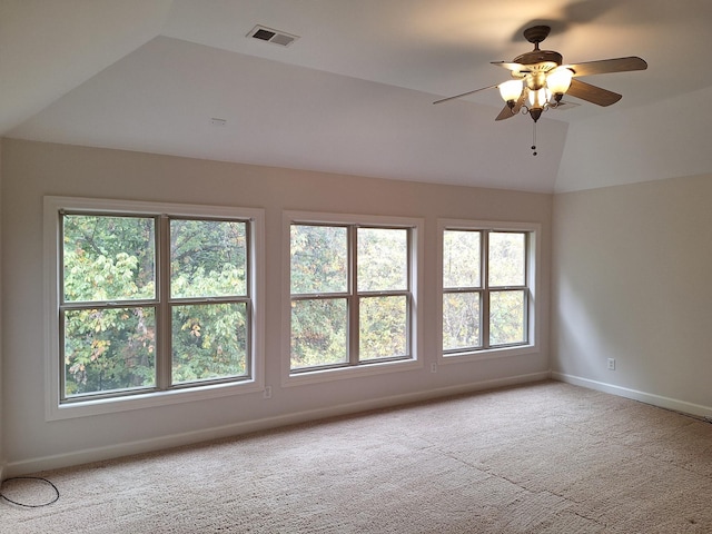 empty room with baseboards, visible vents, a ceiling fan, vaulted ceiling, and carpet floors