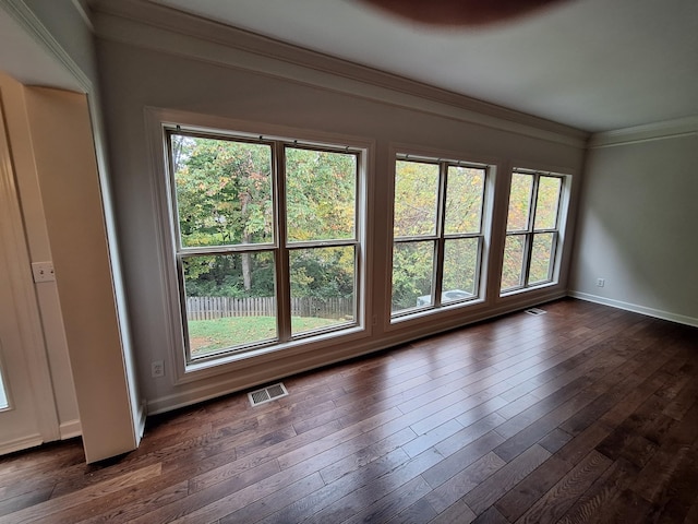 spare room featuring baseboards, visible vents, dark wood-type flooring, and crown molding