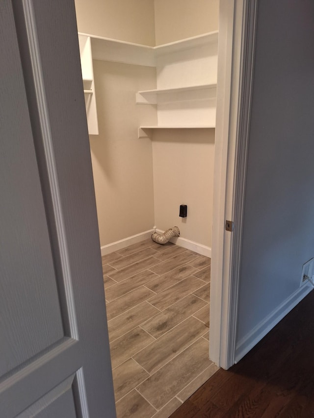 clothes washing area featuring baseboards, laundry area, and wood tiled floor