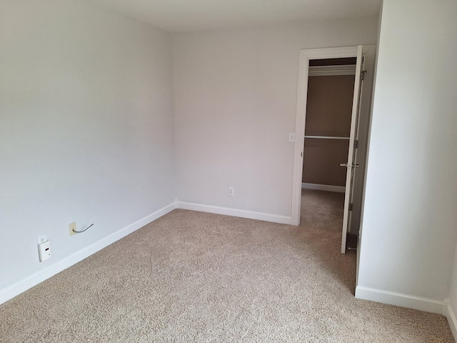 spare room featuring light carpet and baseboards